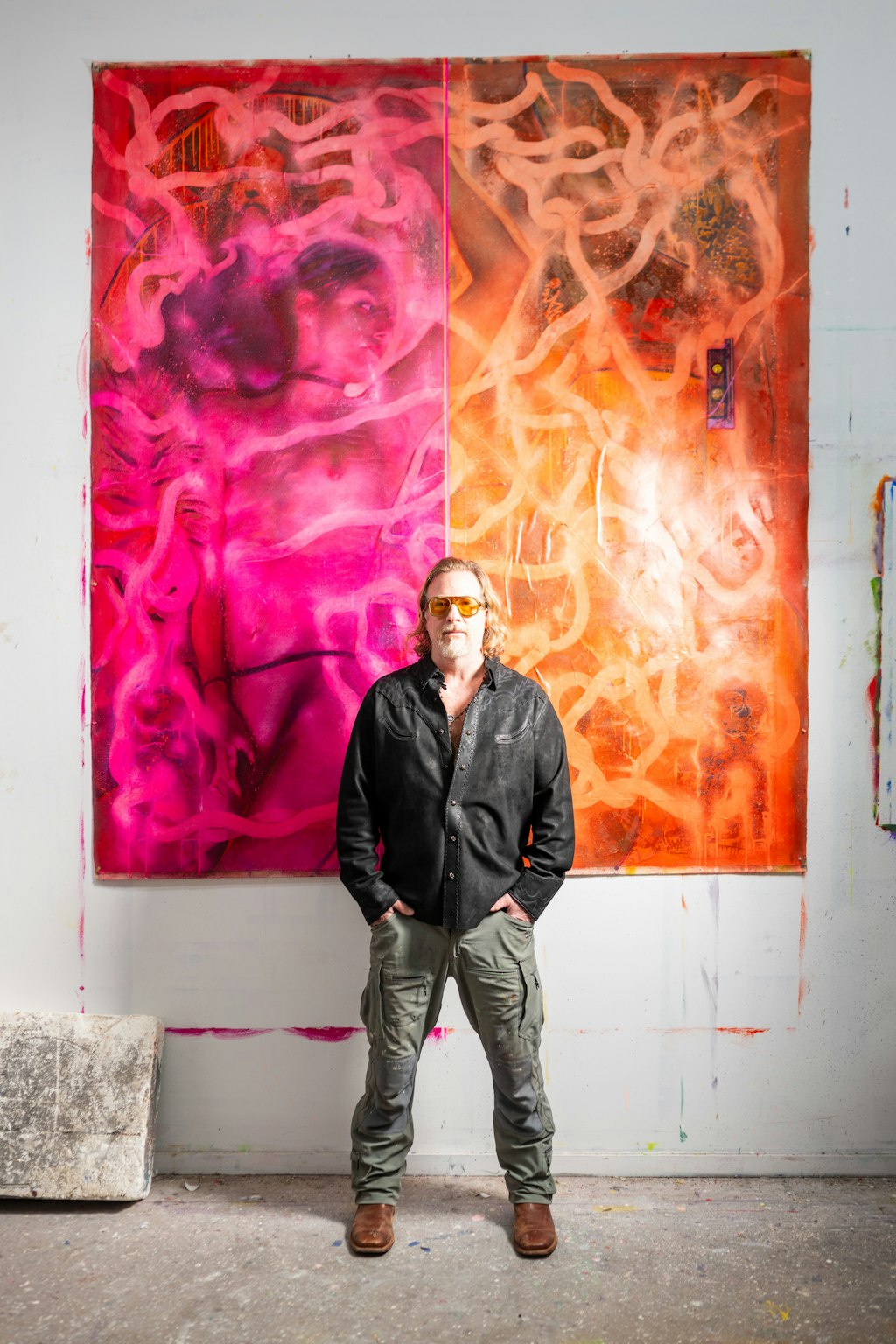 Person standing in front of a large abstract painting with vibrant pink and orange colors.