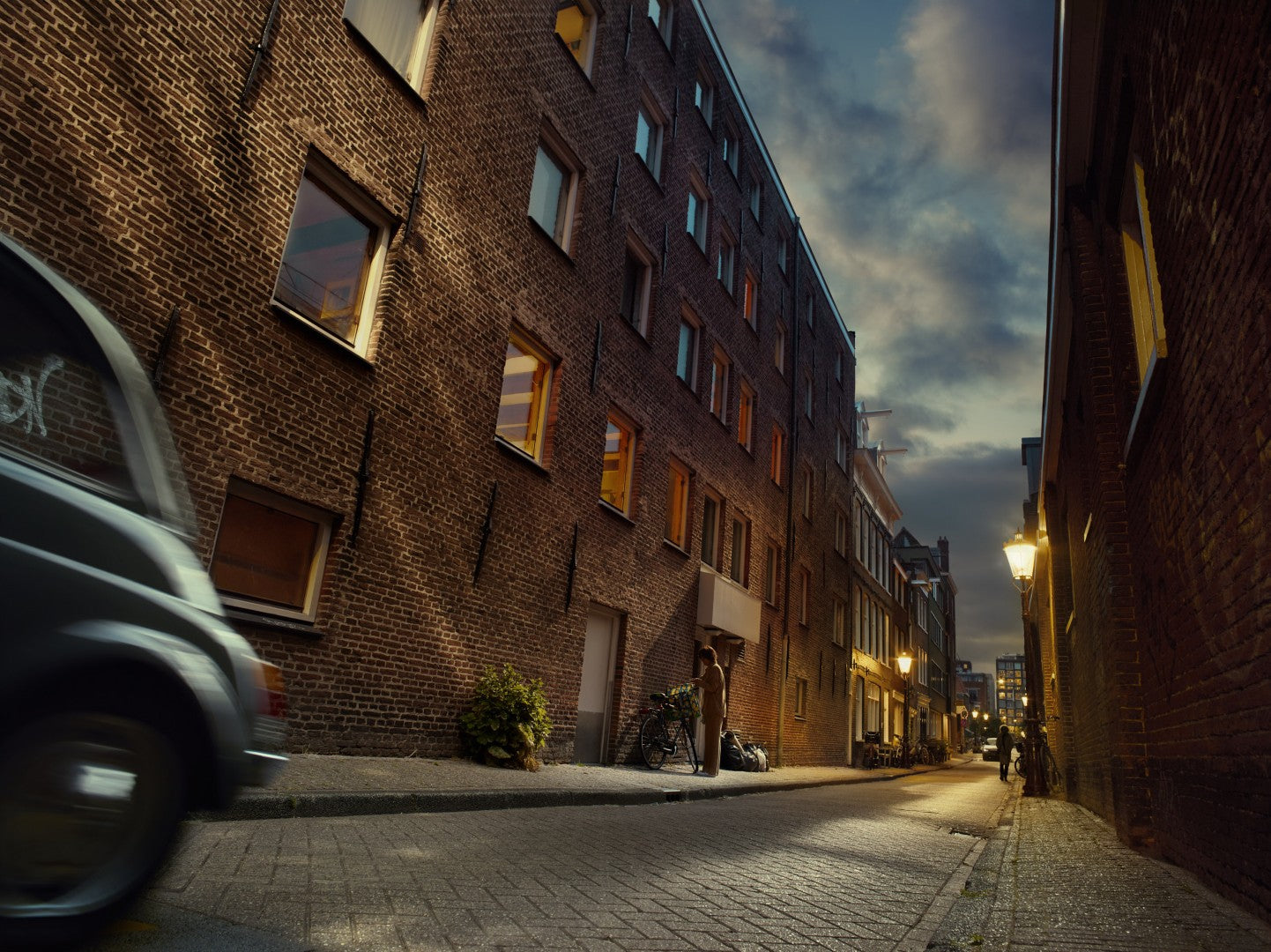 Narrow street with brick buildings and a car on a cloudy day