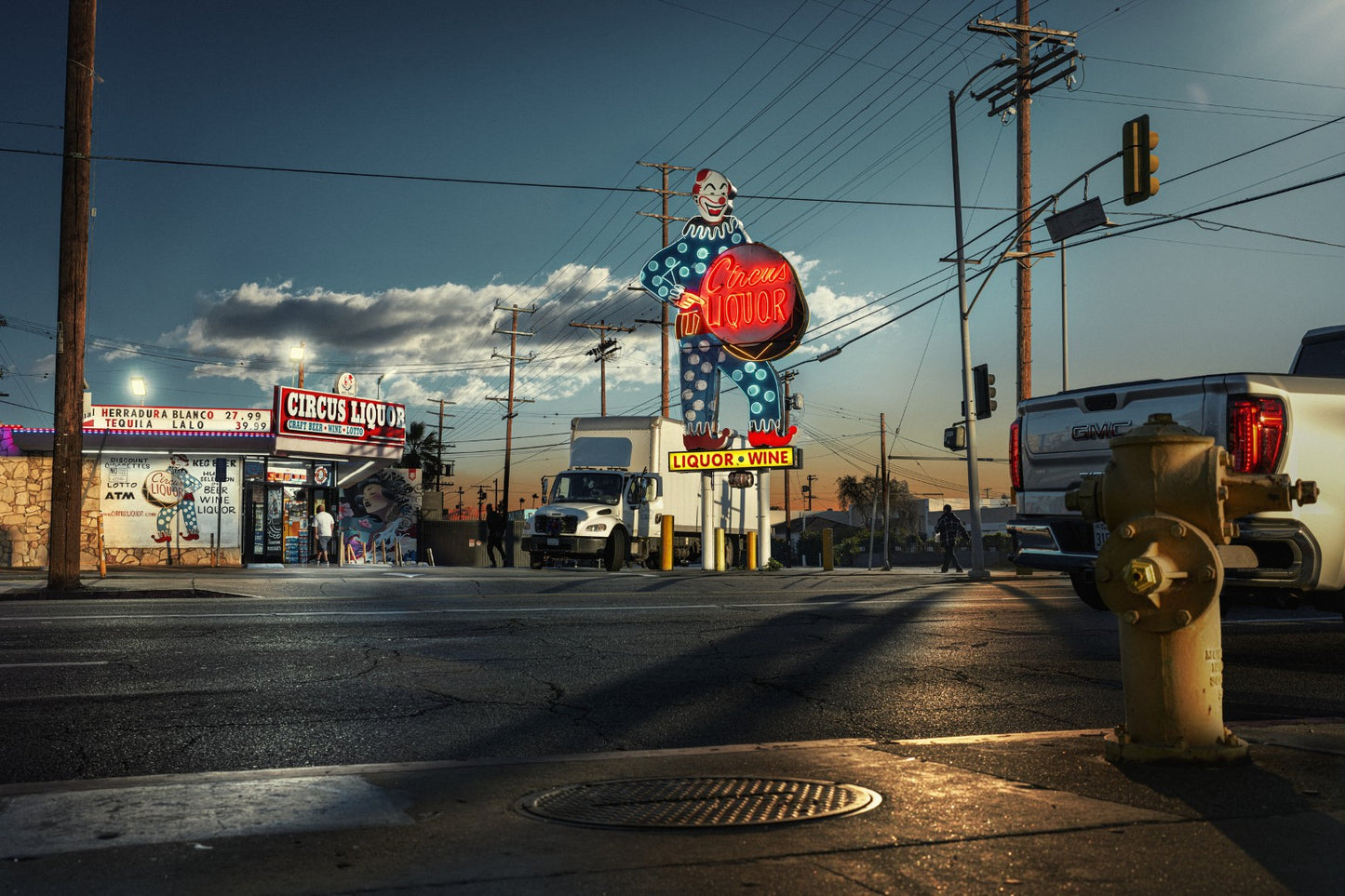 Street scene with a large neon sign and various businesses in the background.