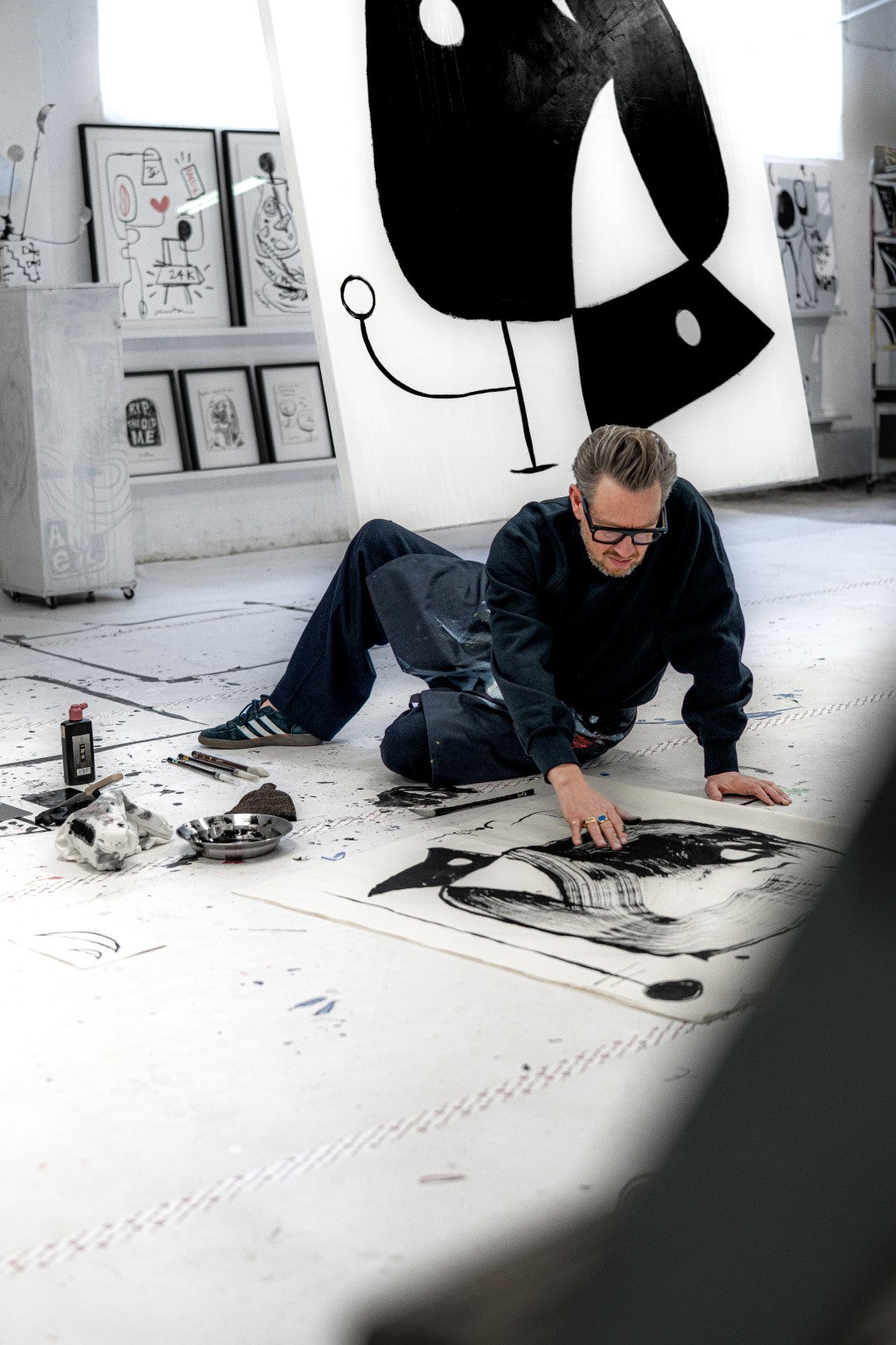 Artist working on a large black and white abstract painting in a studio.