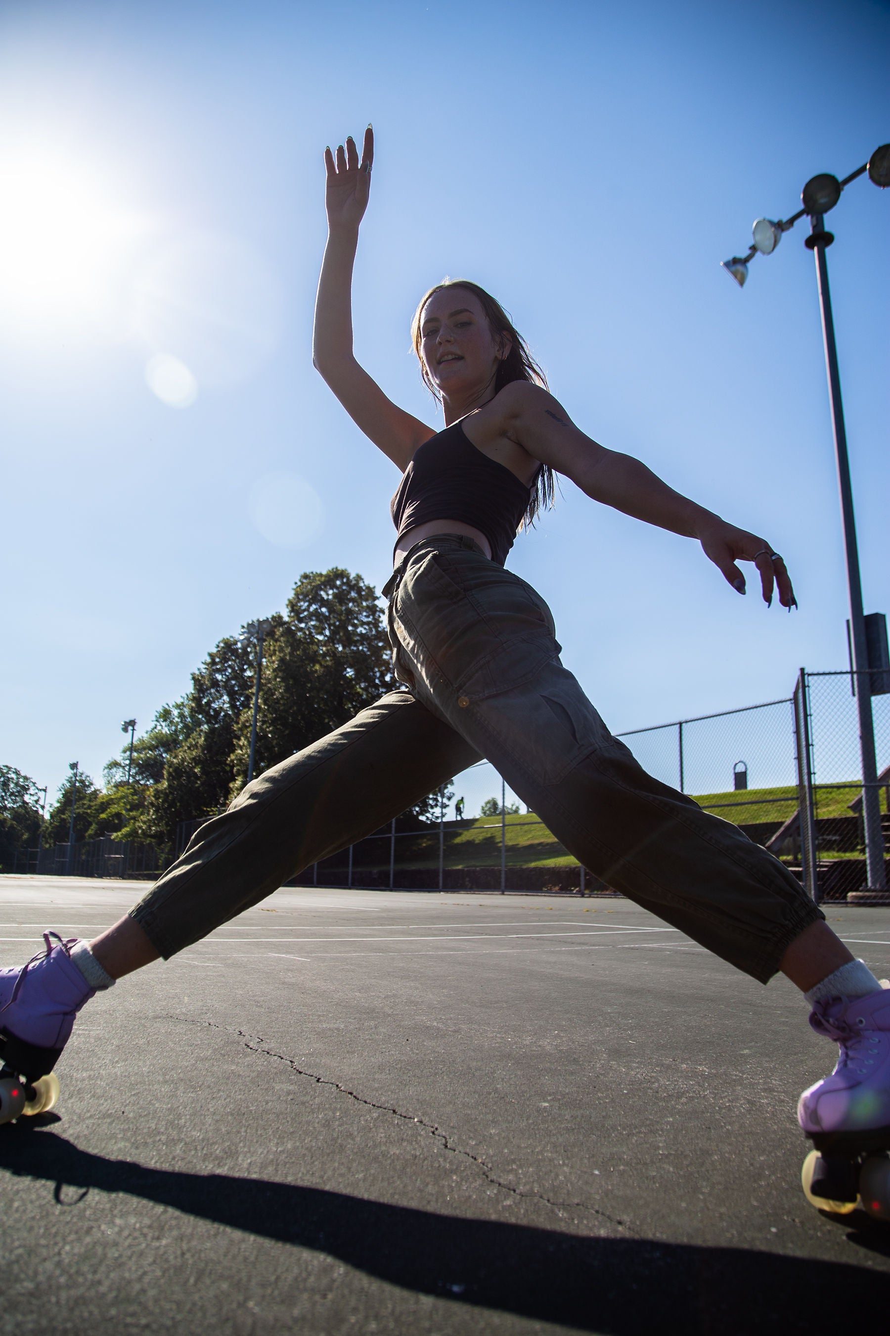 Person in roller skates performing a wide-leg split pose on an outdoor court.