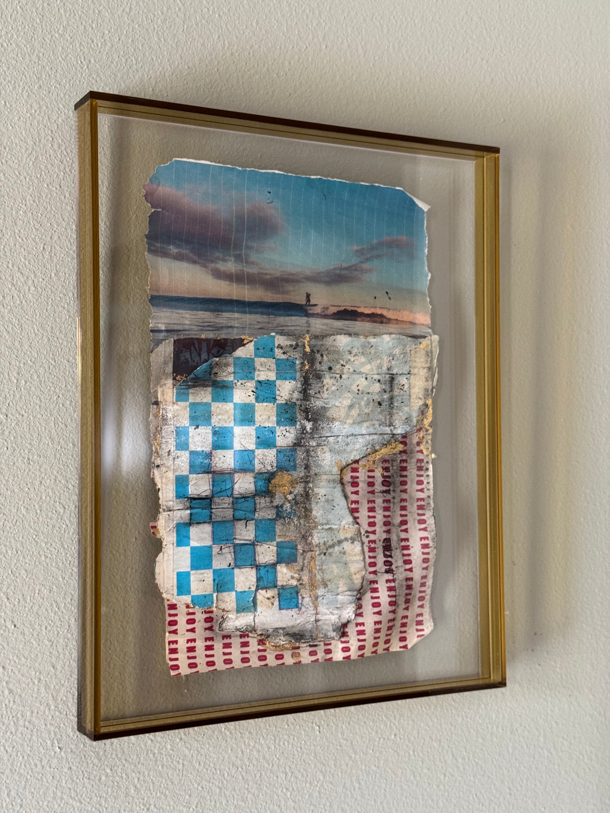 Framed textile artwork with checkered pattern on a plain wall