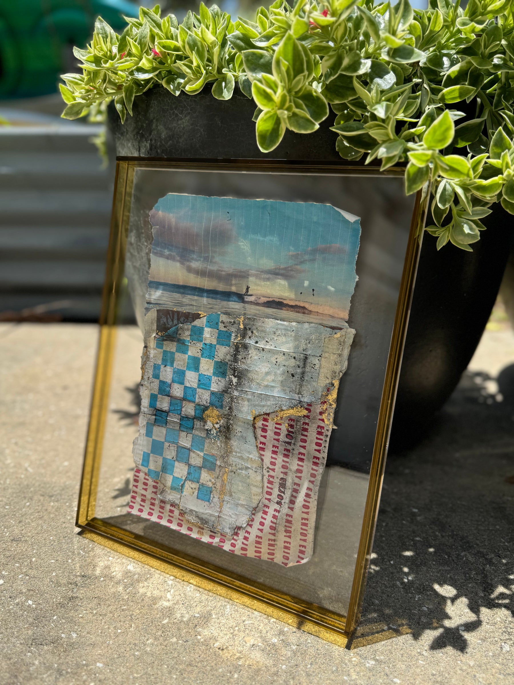 Small framed artwork with fabric textures on a concrete surface