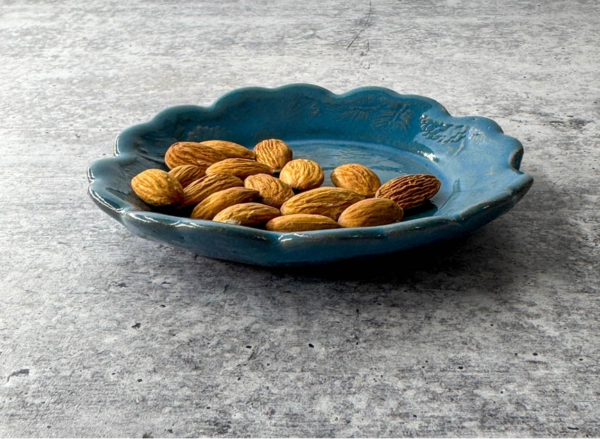 blue plate with scalloped edge and almond on grey background