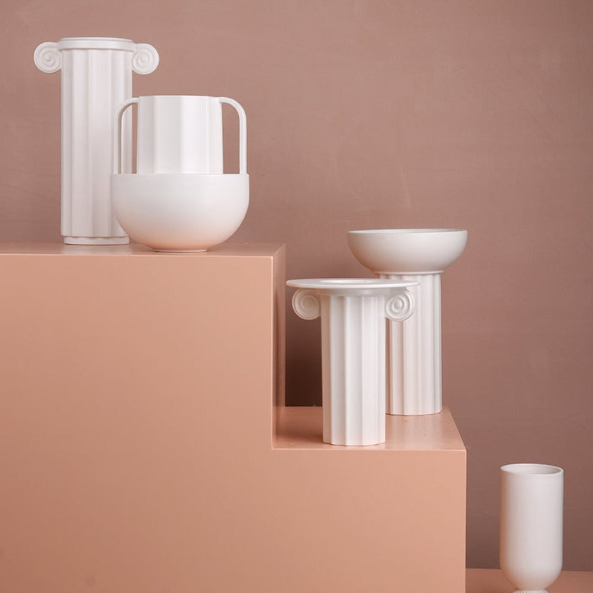 white Greek inspired vases on coral colored display