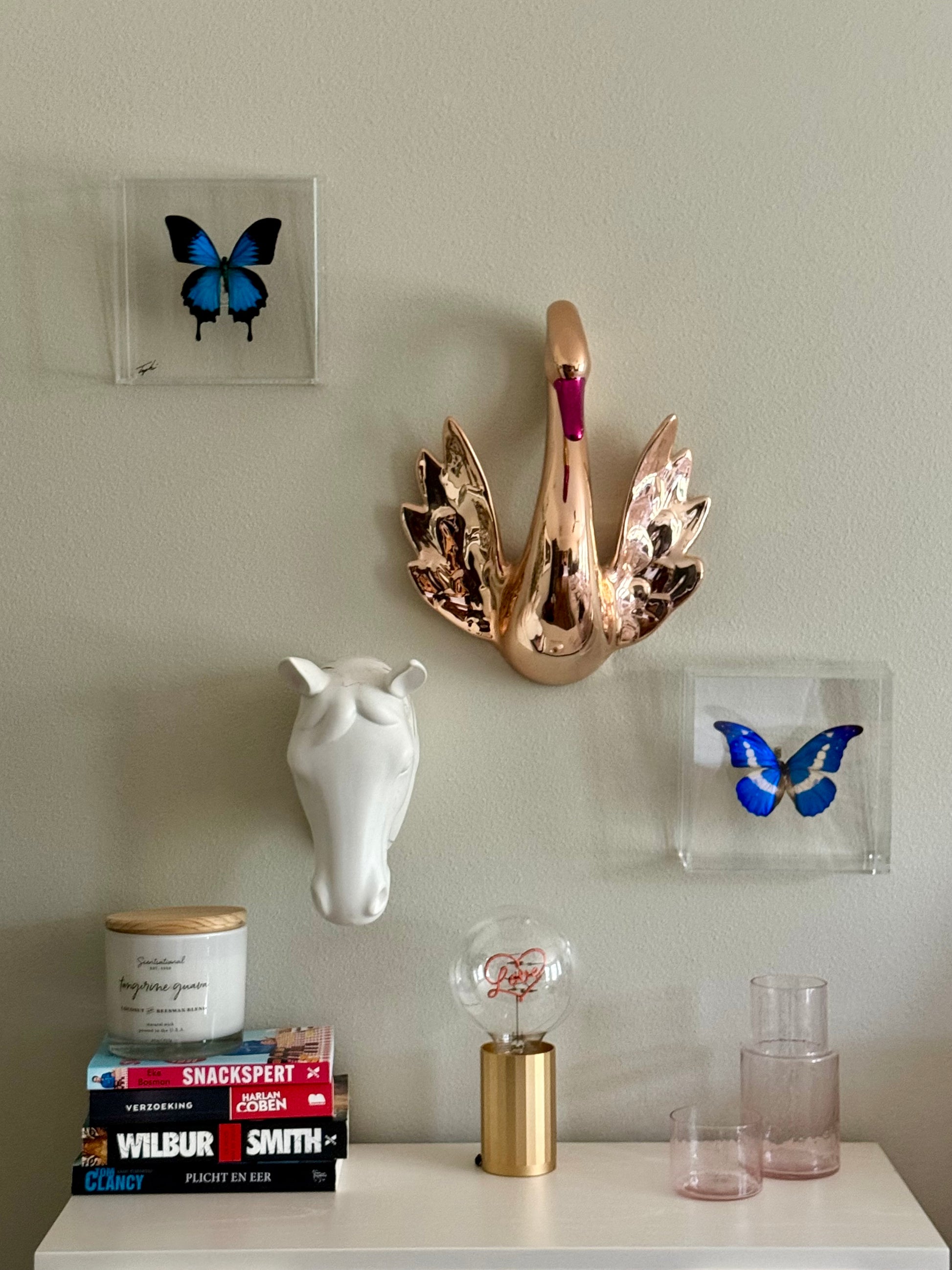 two blue mounted butterflies hanging among other home decor pieces.
