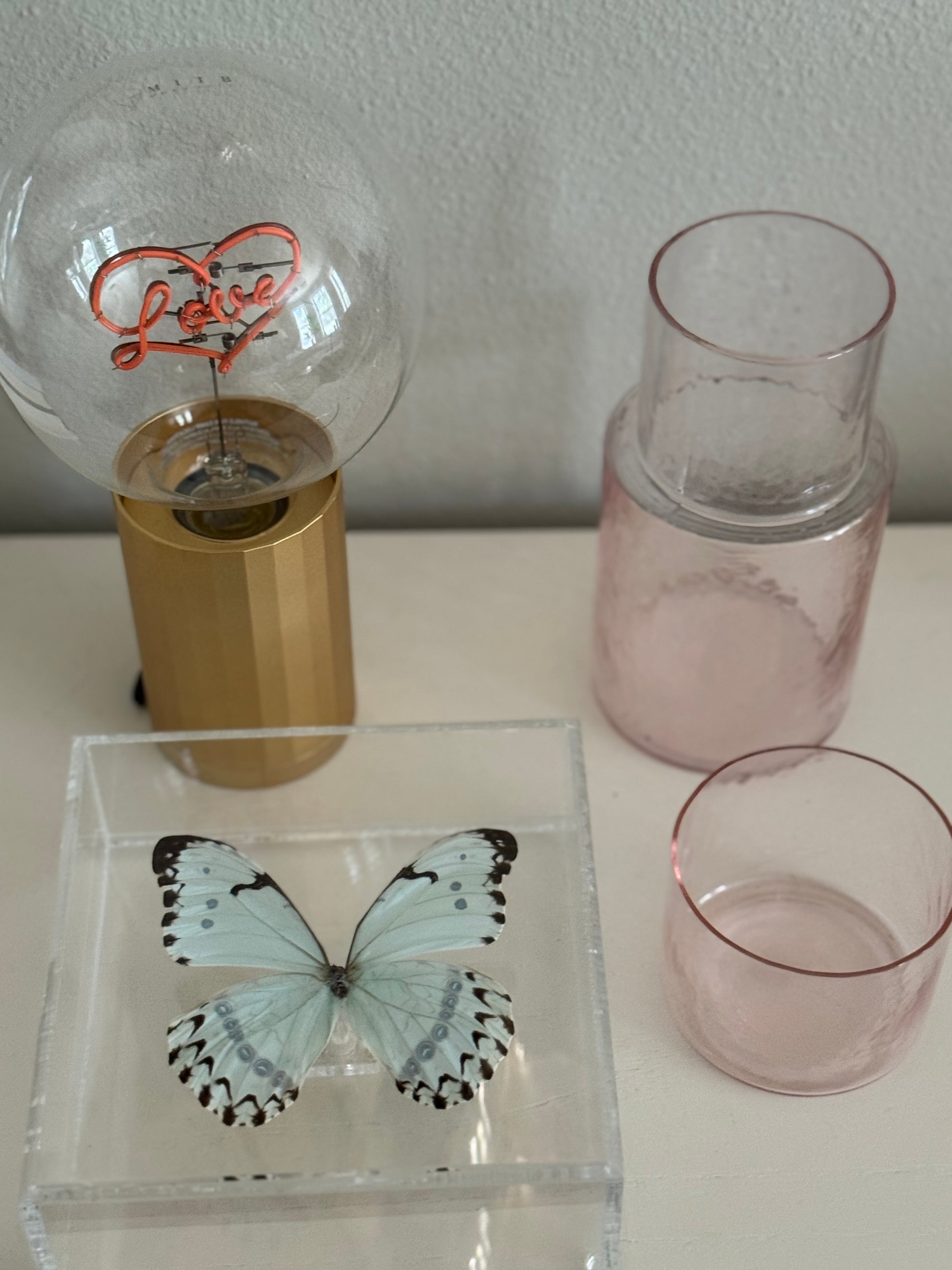light blue and black butterfly mounted in an acrylic shadowbox laying flat on a decorated table.