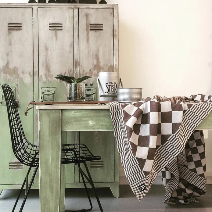 wooden locker cabinet, green table black metal chair and brown and white checkered tablecloth