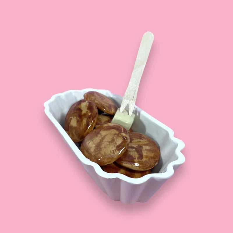 ceramic sculpture of Dutch poffertjes in whte sculptured container with wooden fork