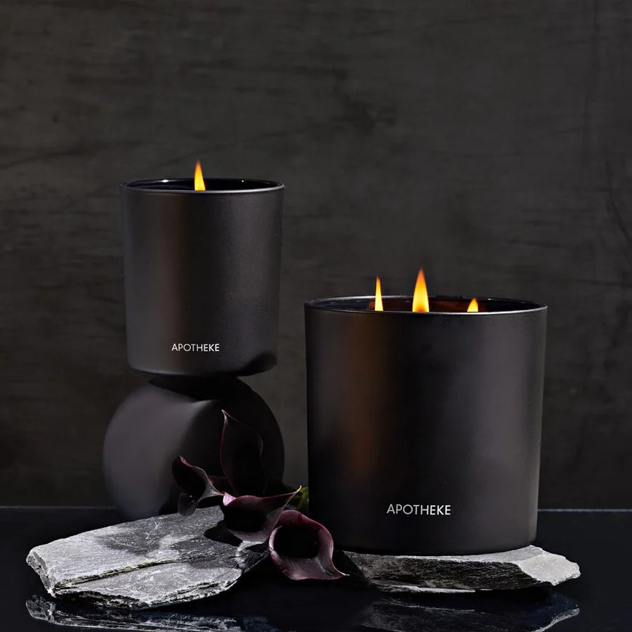 black vessels with Apotheke logo and burning candles on black back ground