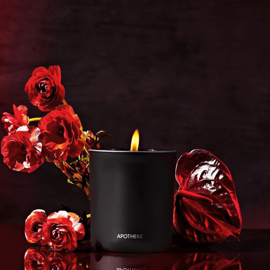 black vessel with burning scented candle and red flowers with black back ground