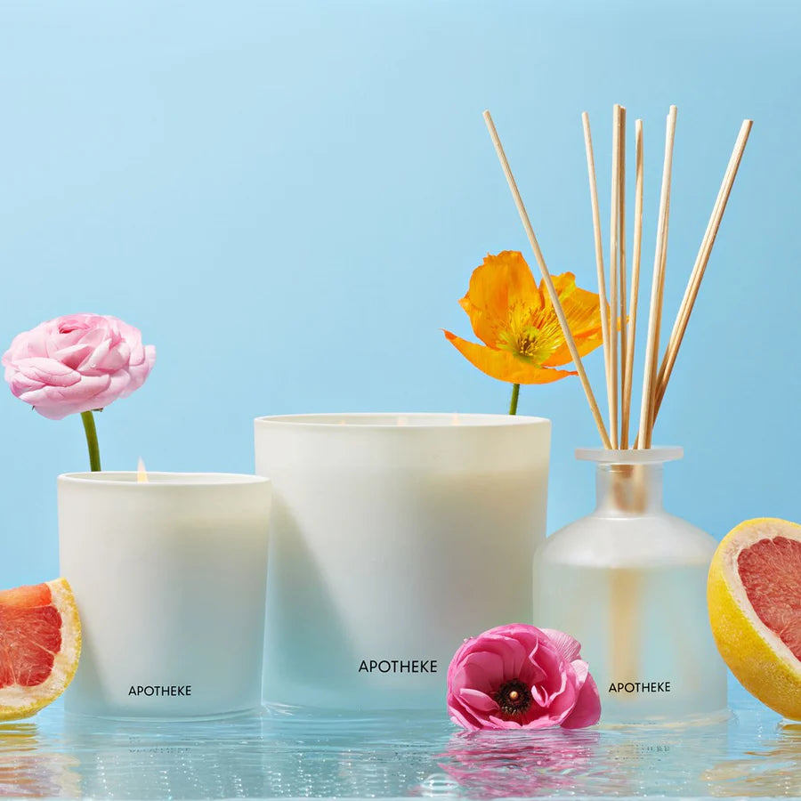scented candles in white glass vessels, reed diffuser flowers and grapefruit in a blue setting
