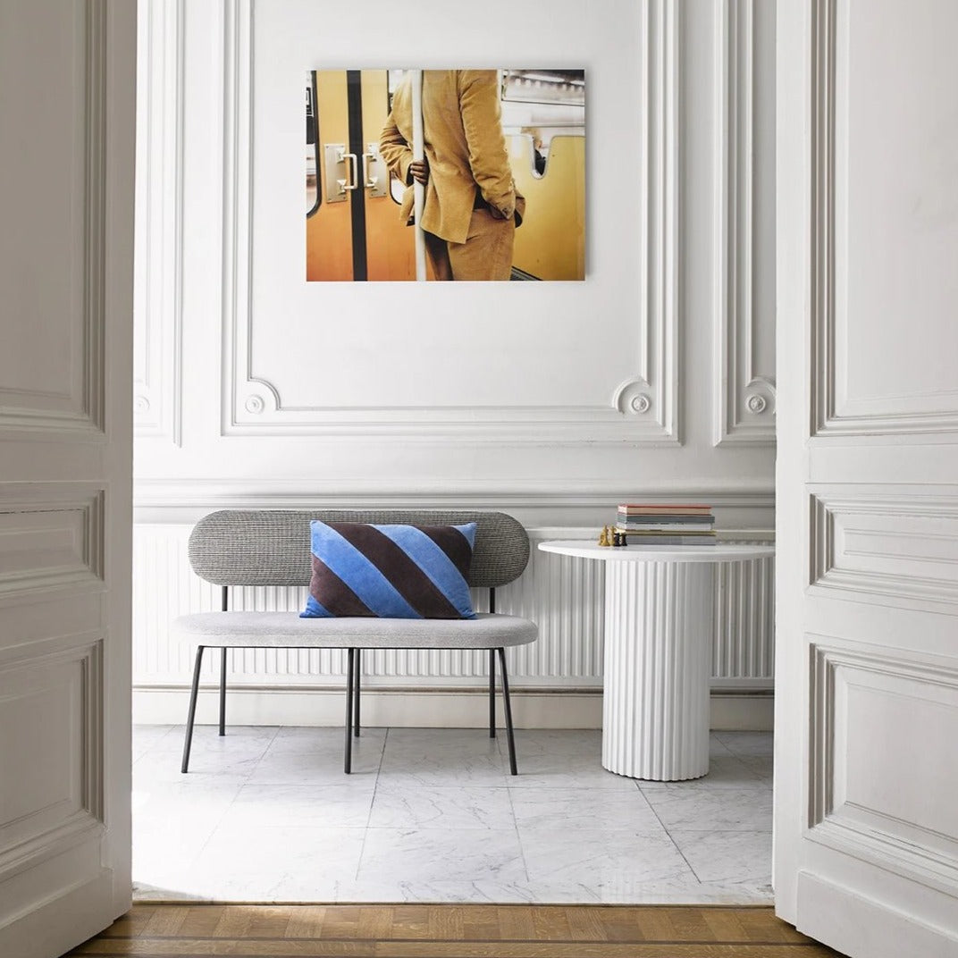 hallway with bench and white pillar table and art work of man in yellow suit