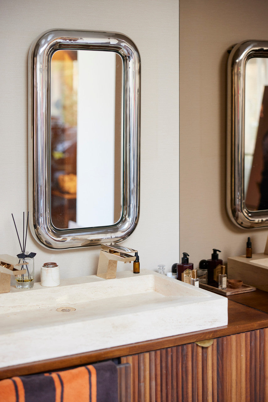 rectangular chrome chubby mirror in bathroom with orange and brown striped towel
