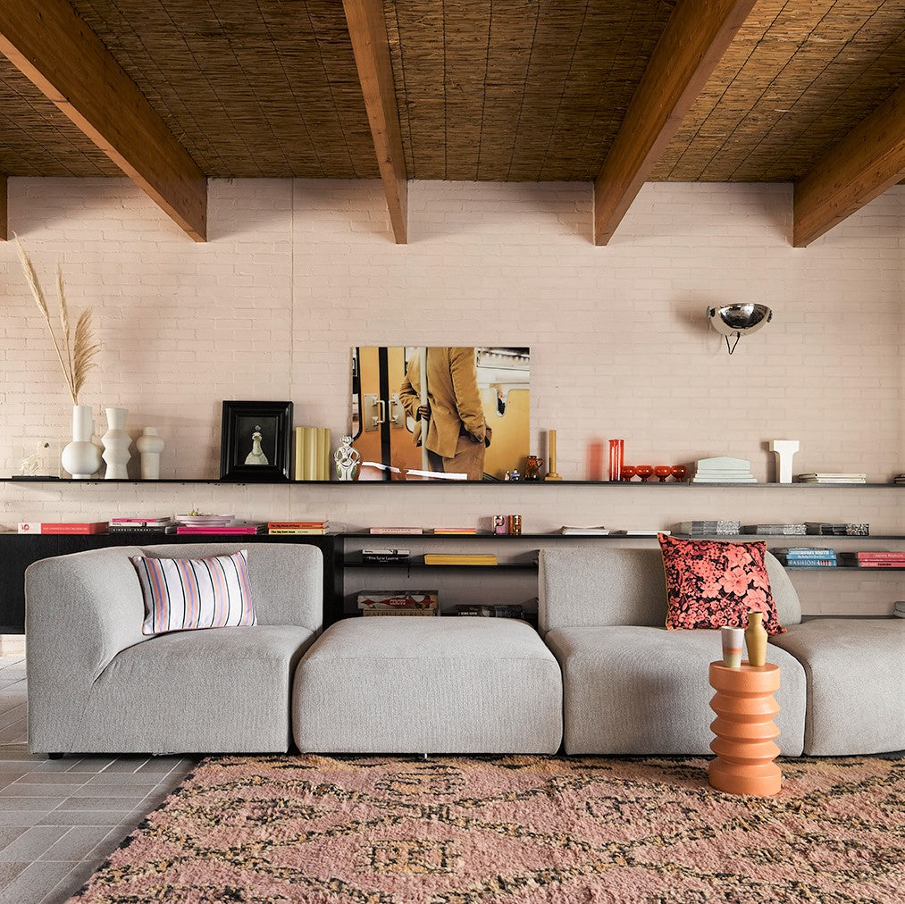 living room with large sofa and open shelving with white flower vases in various shapes