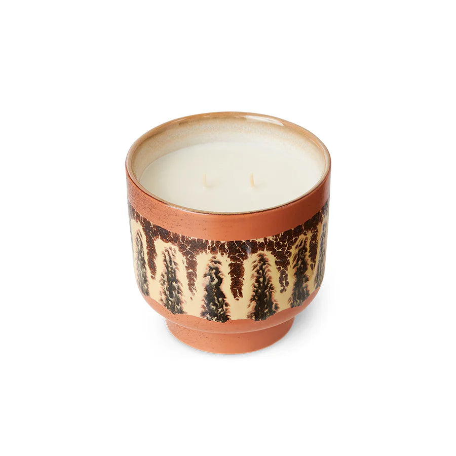 Candle in a terracotta container with decorative pattern on a white background