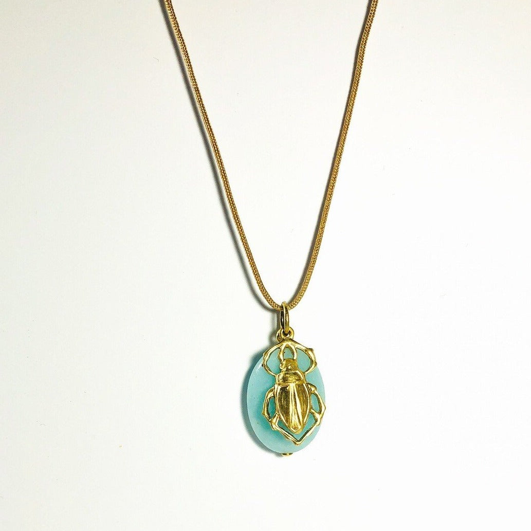 close up of brass beetle on blue stone hanger