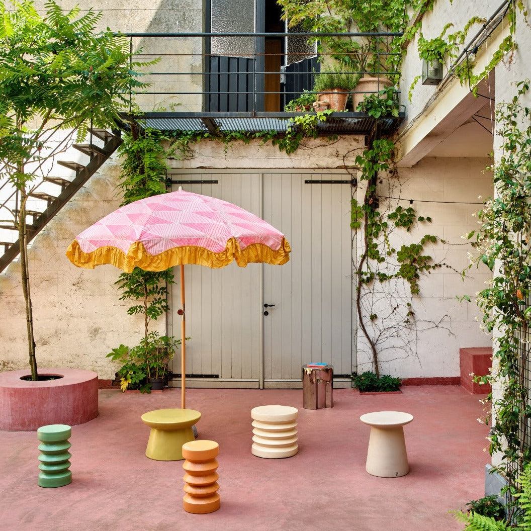 colored stoneware accent tables on pink outdoor patio floor with pink parasol
