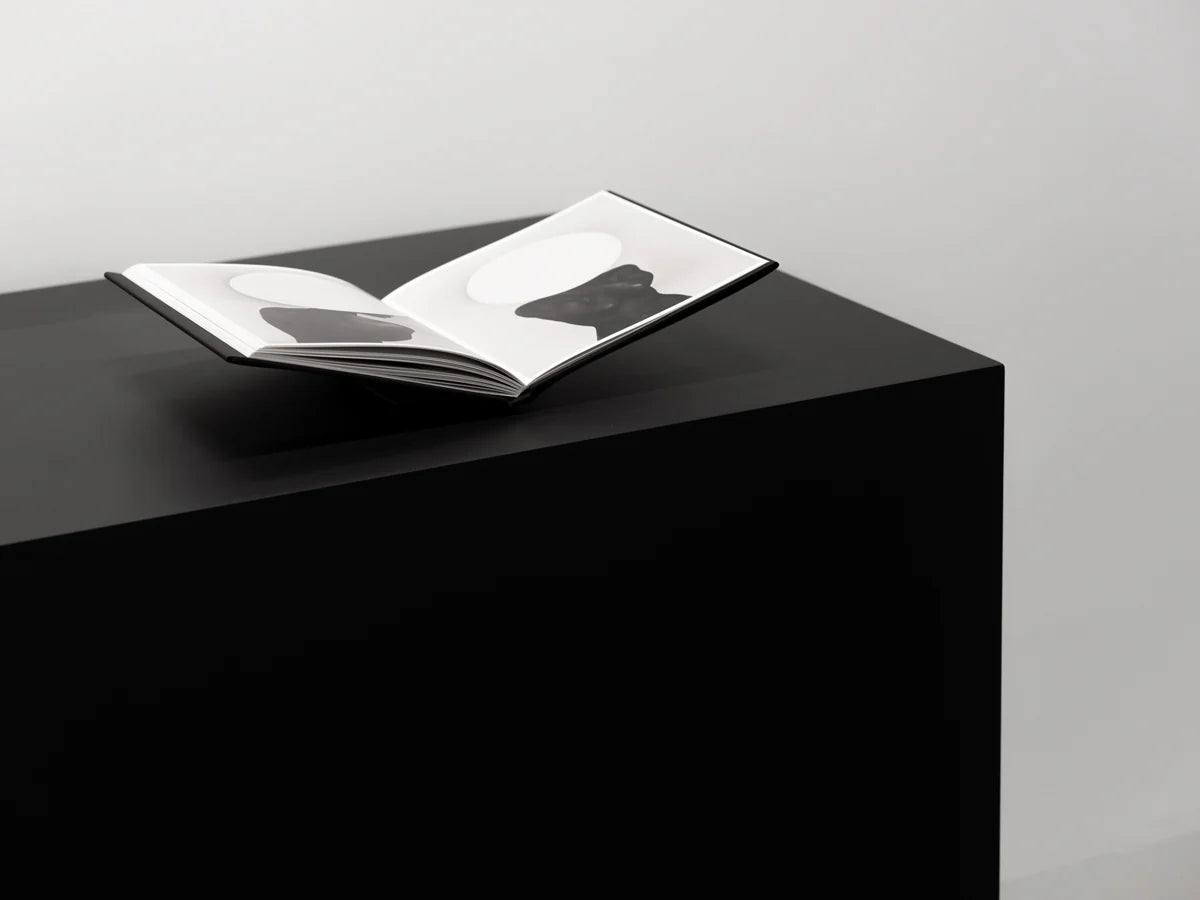 Open book on a black pedestal with a gray background