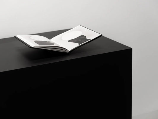 Open book on a black pedestal with a gray background