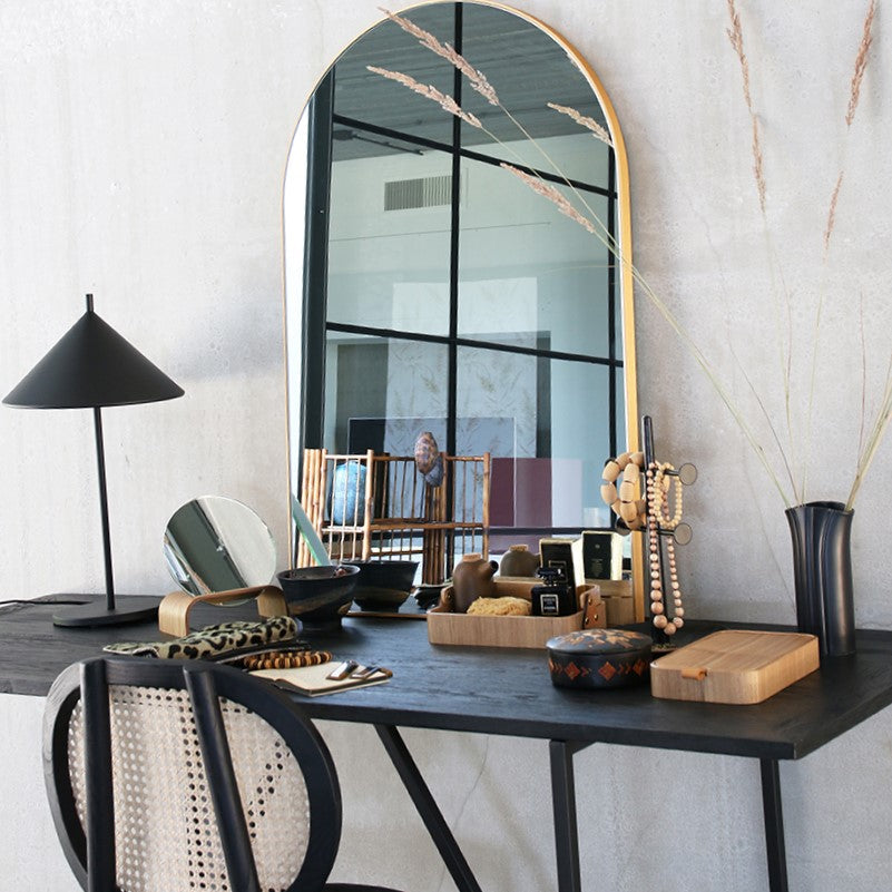 vanity with large arch shaped mirror and a black wooden jewelry standard with bracelets