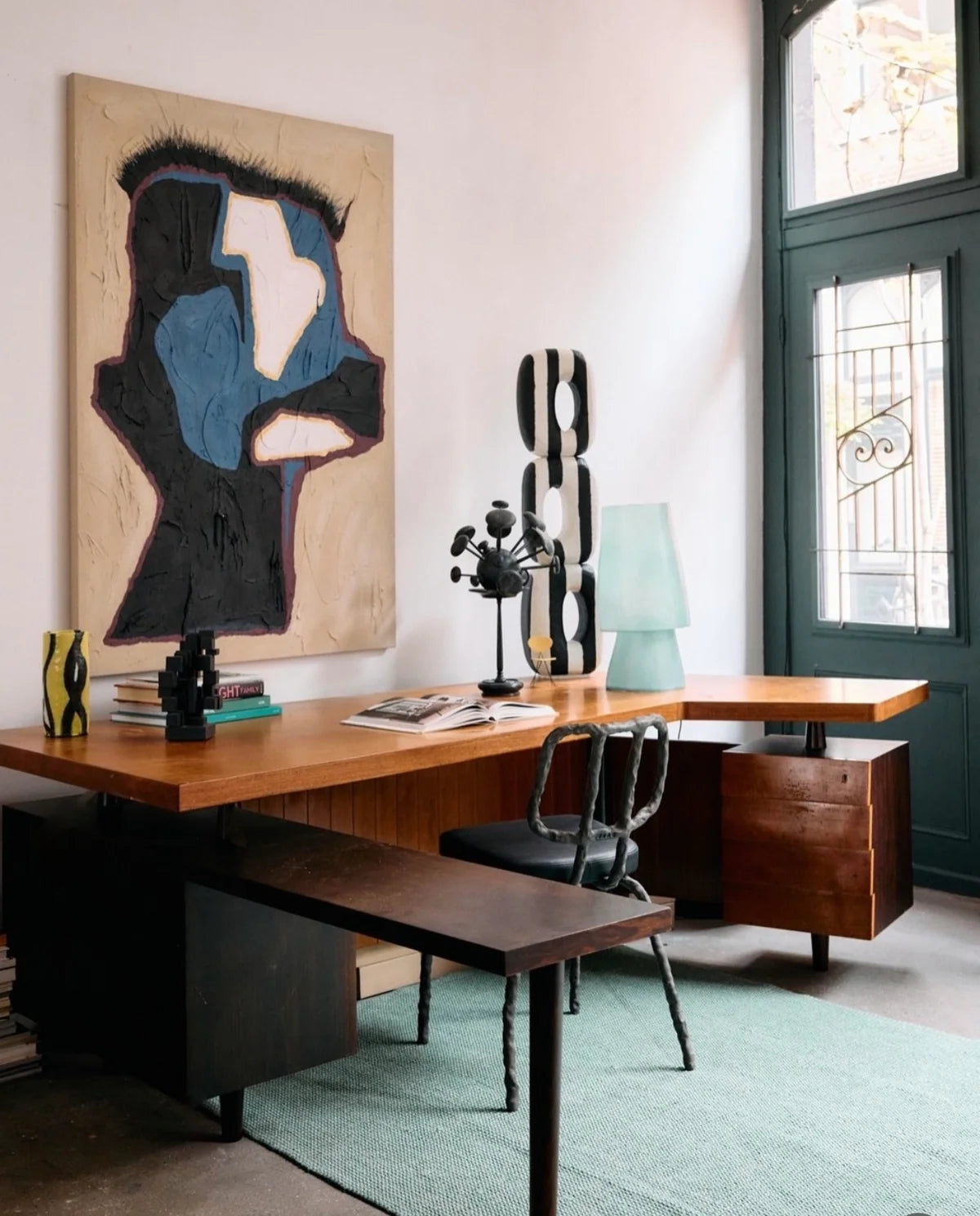 office with painting, chair blue lamp and black and white sculpture