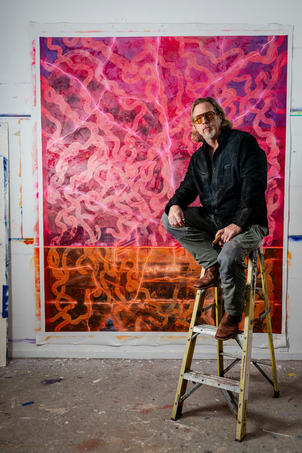 Man sitting on a ladder in front of a colorful abstract painting