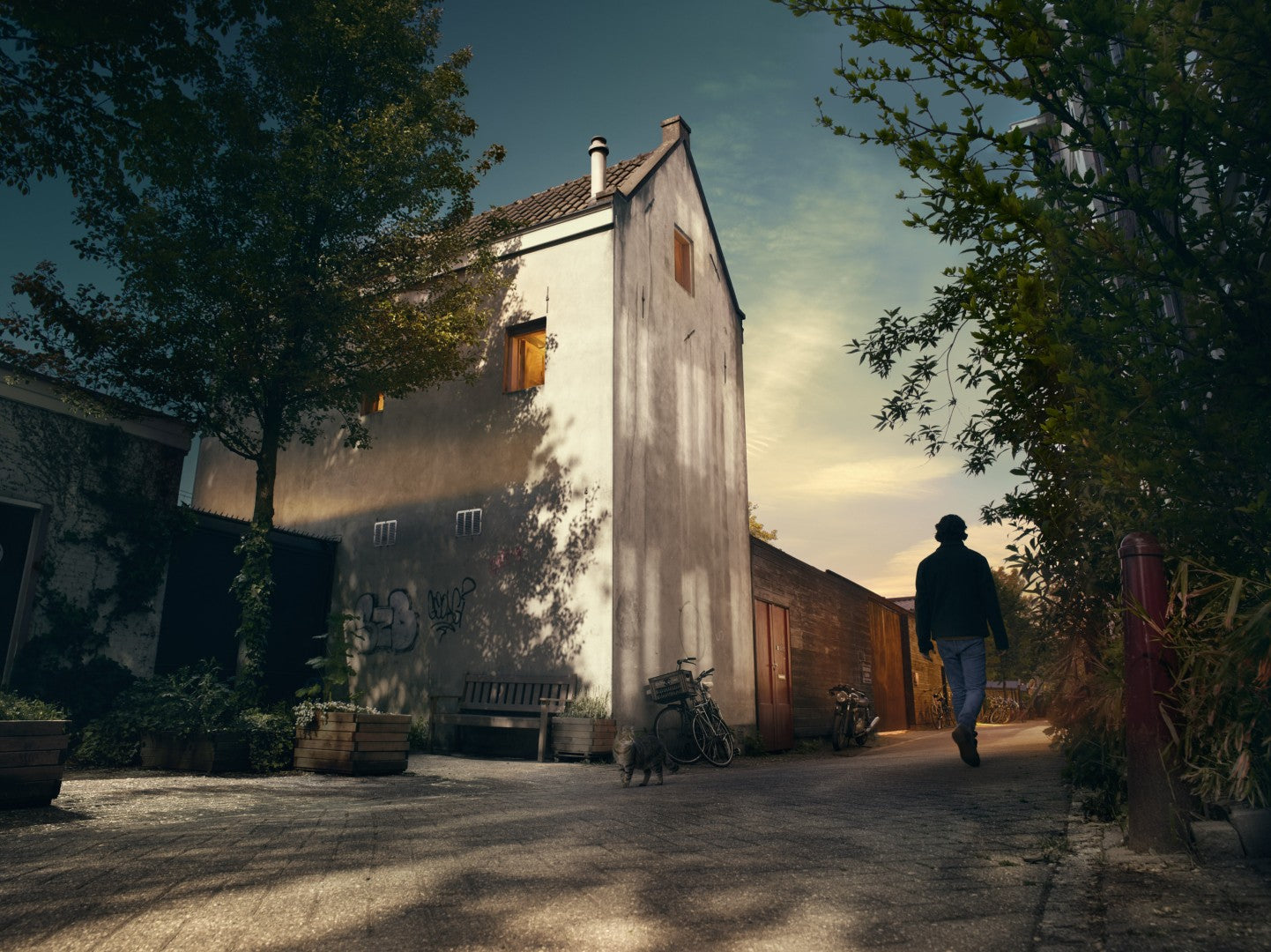 Person walking towards a large building with trees and a clear sky.