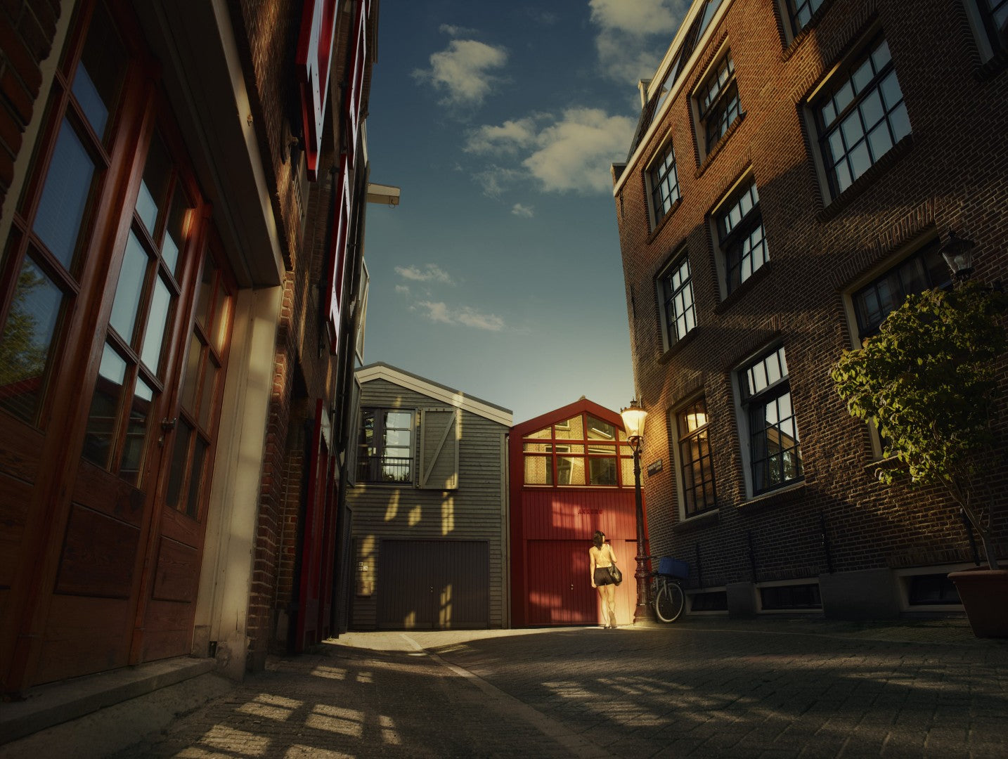 Narrow street with brick buildings and a person walking in the evening.