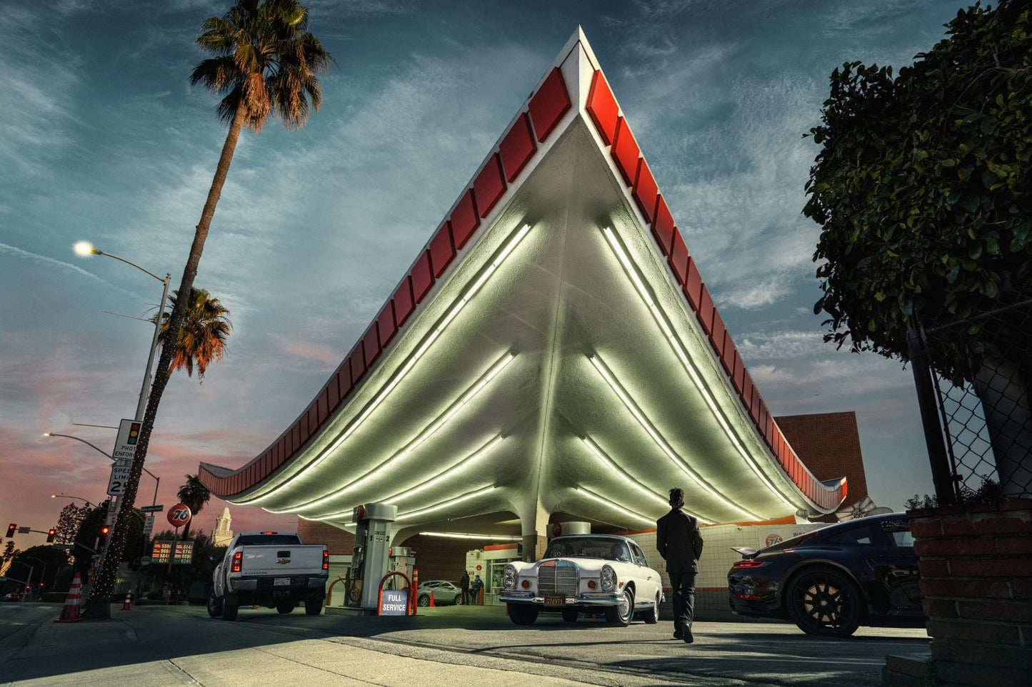 Vintage gas station with a distinctive roof design under a twilight sky.
