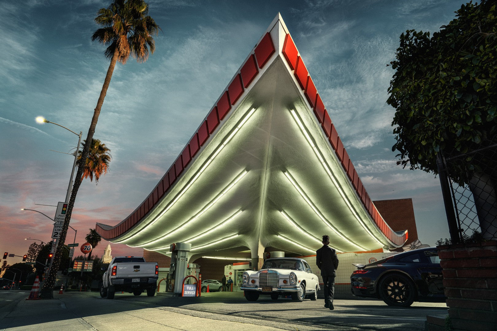 Vintage gas station with a distinctive roof design under a twilight sky.