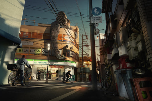 Urban street scene with a large Godzilla statue on a building, people on bicycles, and various street elements.