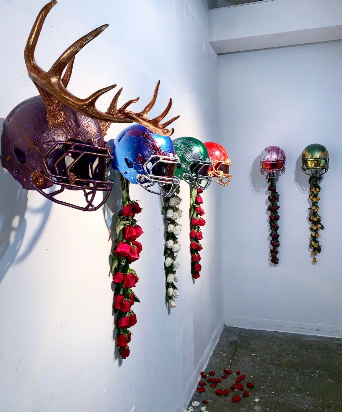 Decorative wall art with metallic helmets and floral arrangements on a white wall.