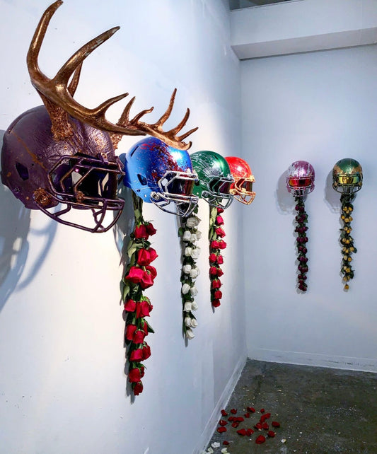 Decorative wall art with metallic helmets and floral arrangements on a white wall.