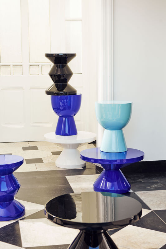 Set of colorful stools with a geometric design on a checkered floor.