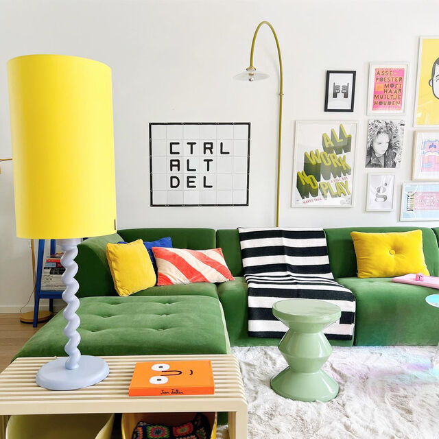 Colorful living room with green sofa, yellow lamp, and various decor items.