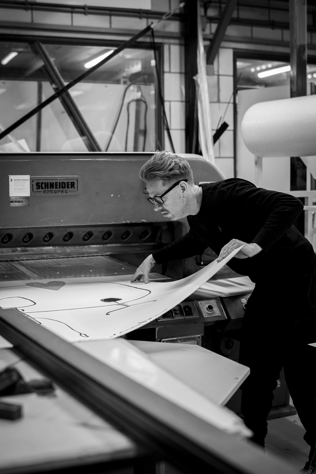 Person working with large paper in a printing press setting