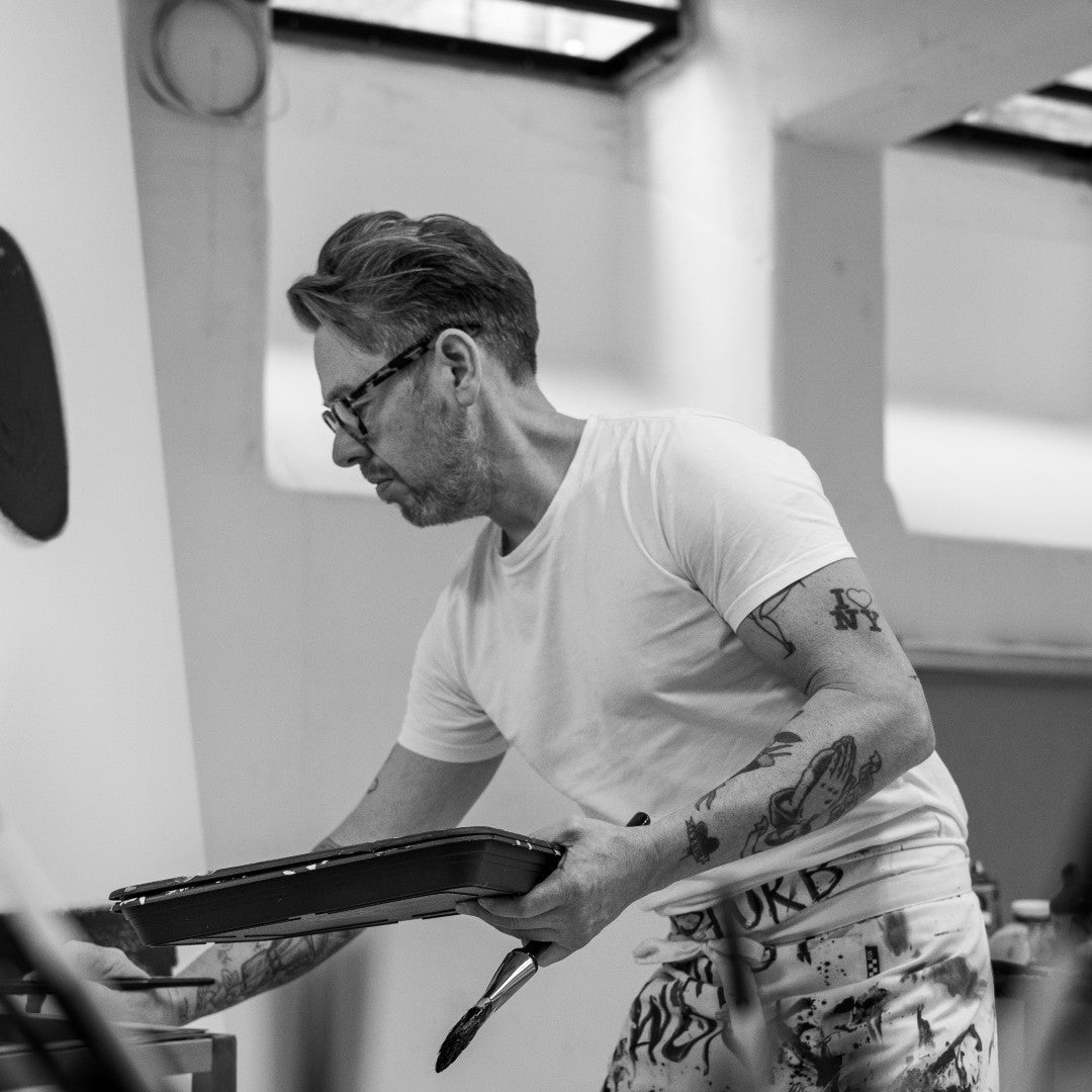 Man with tattoos holding a tray in a kitchen setting