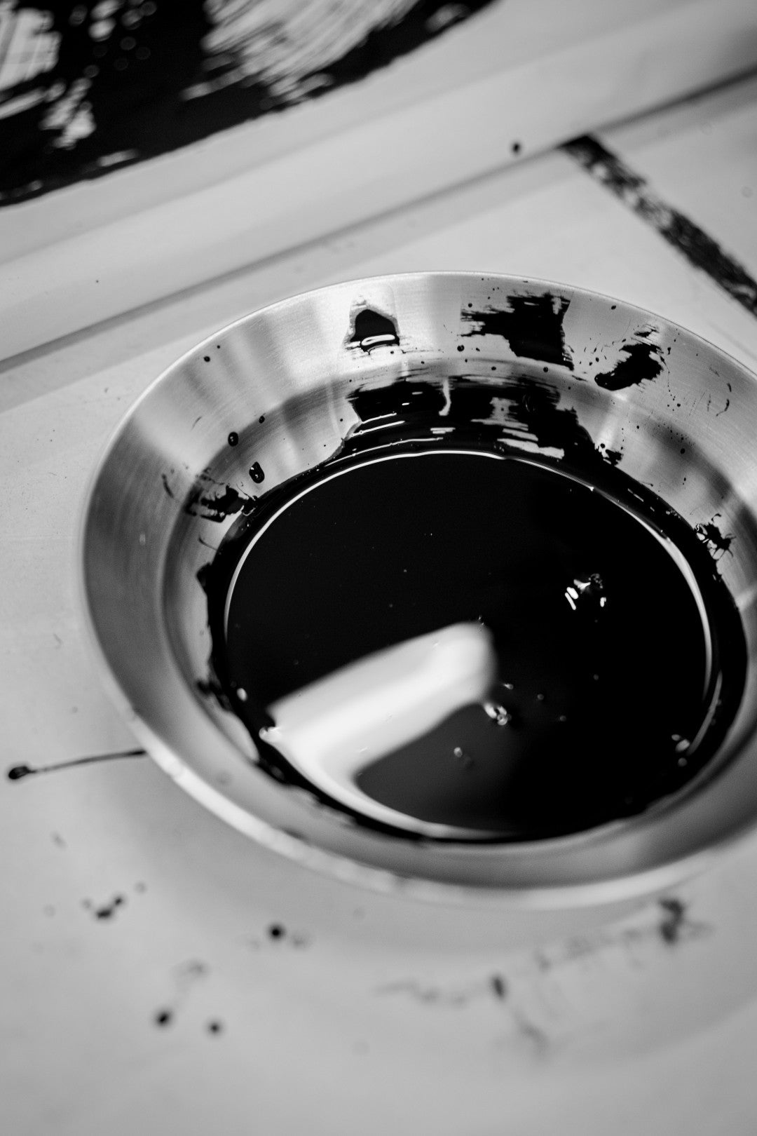 Close-up of a metallic bowl filled with black paint