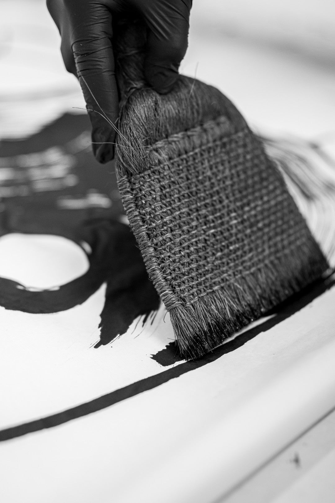 Person painting with a brush, wearing black gloves