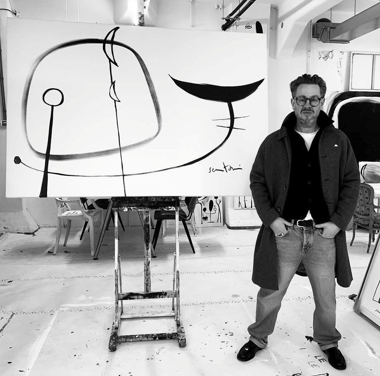 Man standing in a studio with a large abstract artwork on an easel 