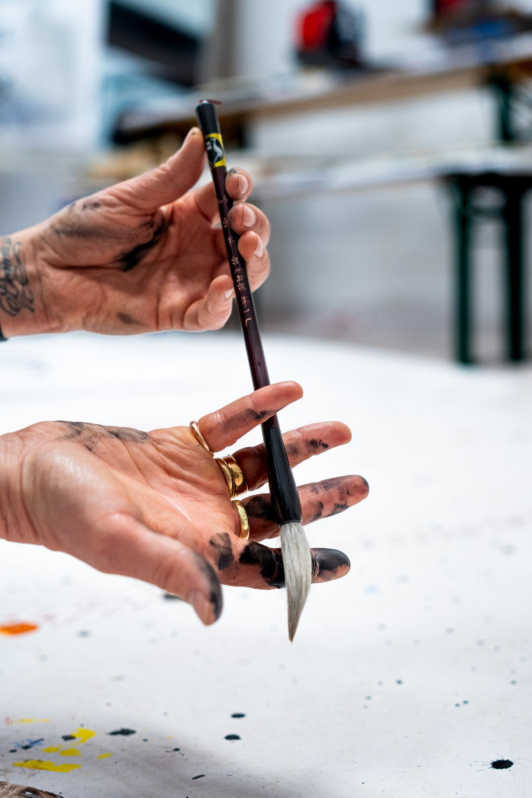 Hand holding a paintbrush with a blurred indoor background