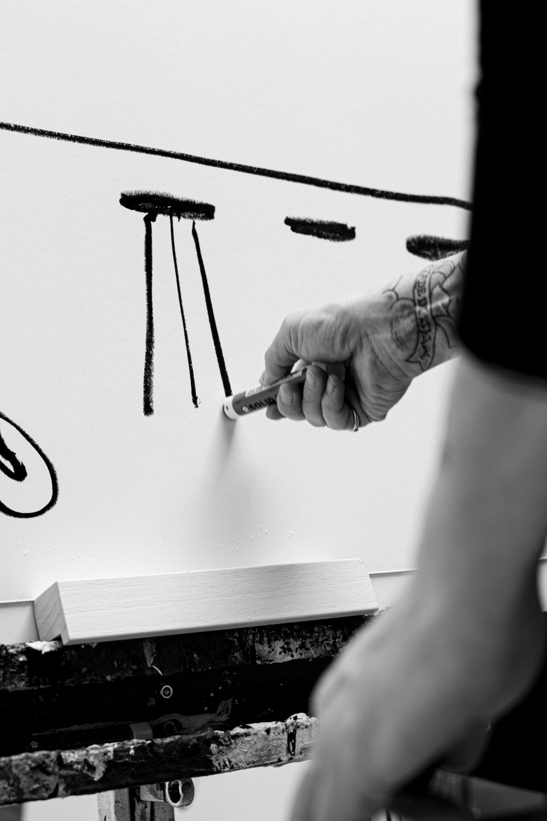 Person holding a marker near a whiteboard with drawings on a light-colored surface
