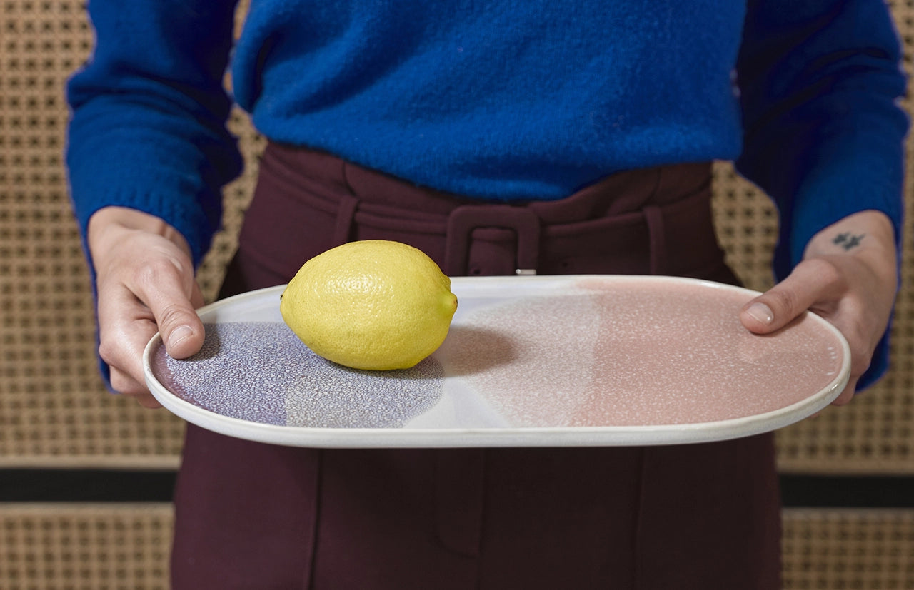 Person holding a tray with a lemon on a patterned background