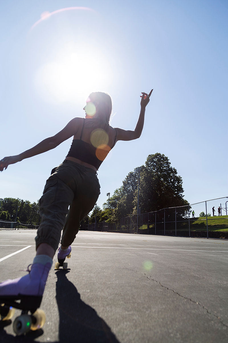Person roller skating outdoors captured from behind with extended arm gesture.