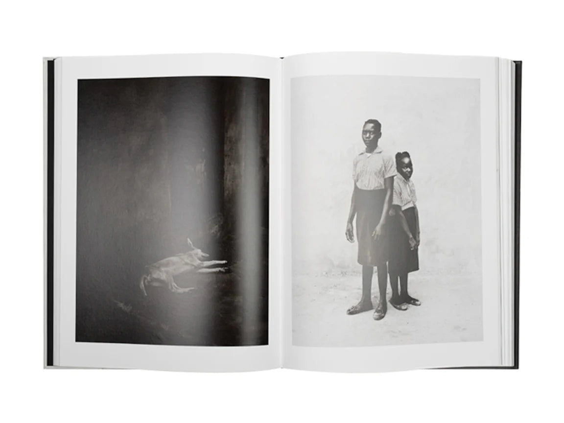 Open book showing black and white photographs of a child and a dog, with a person standing behind them.