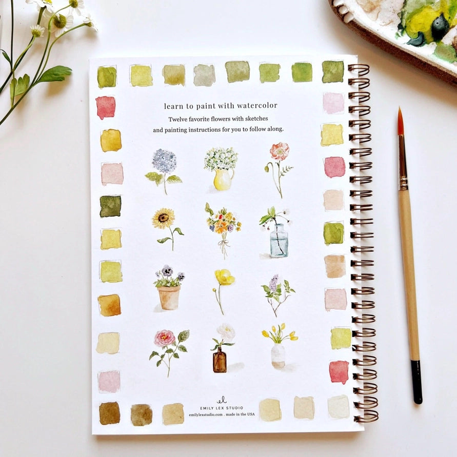 spiral book with flower and color illustrations with paintbrush on white background