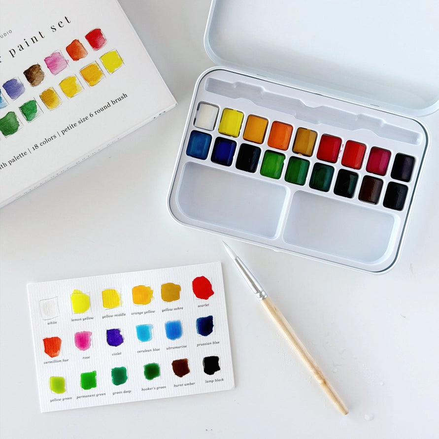 watercolor paint blocks in a metal tin on a white background