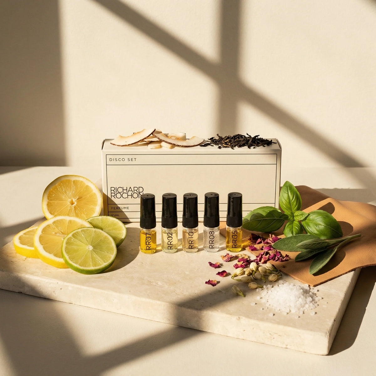 Set of Richard Mille perfume bottles with citrus fruits and leaves on a light surface
