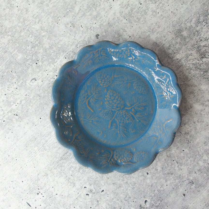 blue plate with scalloped edge on grey background